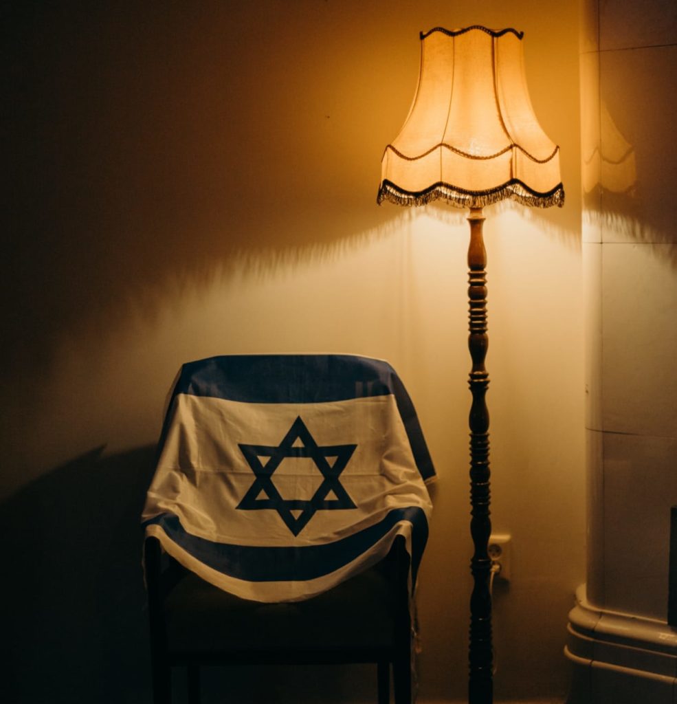 Bandiera israeliana su sedia e luci soffuse, un ricordo di una persona cara, eredità e successione in israele è un'arma a doppio taglio